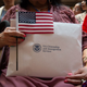 A woman holds the flag and her paperwork as the US Citizenship and Immigration Services welcomes 200 new citizens from 50 countries during a ceremony in honor of Independence Day at the New York Public Library on July 3, 2018, in New York.